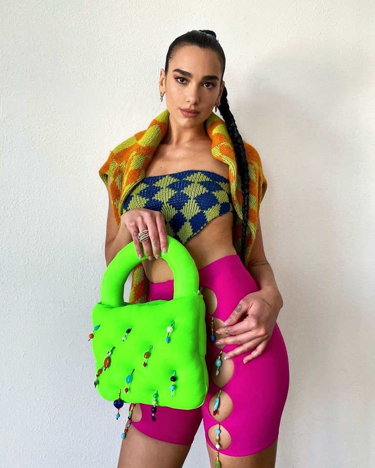 Dua Lipa in a colorful ensemble displaying a large neon green bag