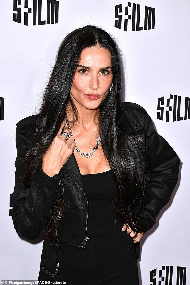 Image description: Demi Moore igniting the red carpet in her form-fitting low-cut black dress and a chic black waxed denim jacket.