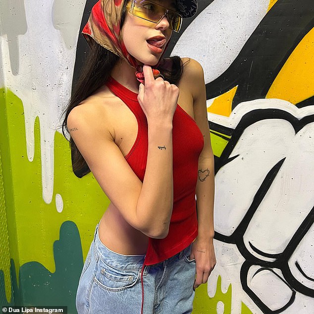 Glamorous Dua Lipa with loose waves and yellow-tinted sunglasses